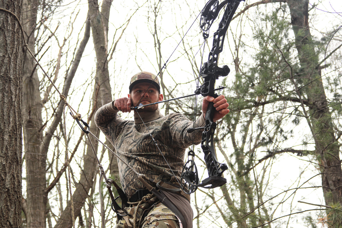The image shows a bow hunter using Latitude Outdoors Saddle while shooting a mathews bow with ARD bow sight. 