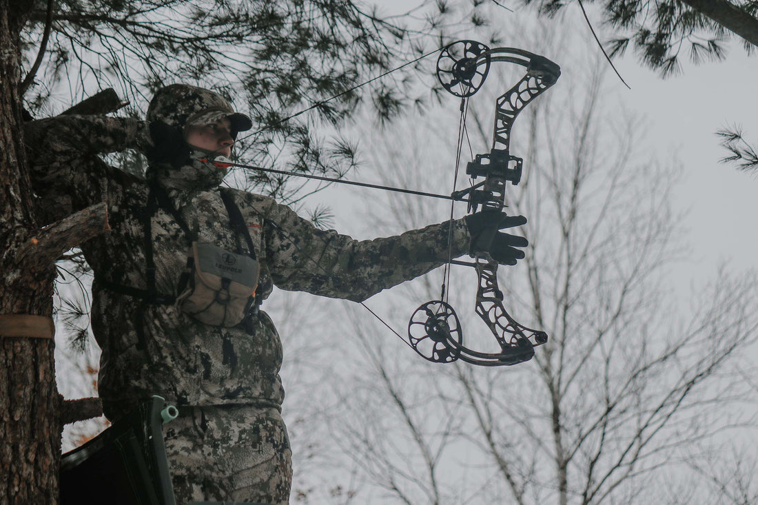 Bow hunter in a tree stand, pulling a Mathews bow back with ARD sight on his bow. 
